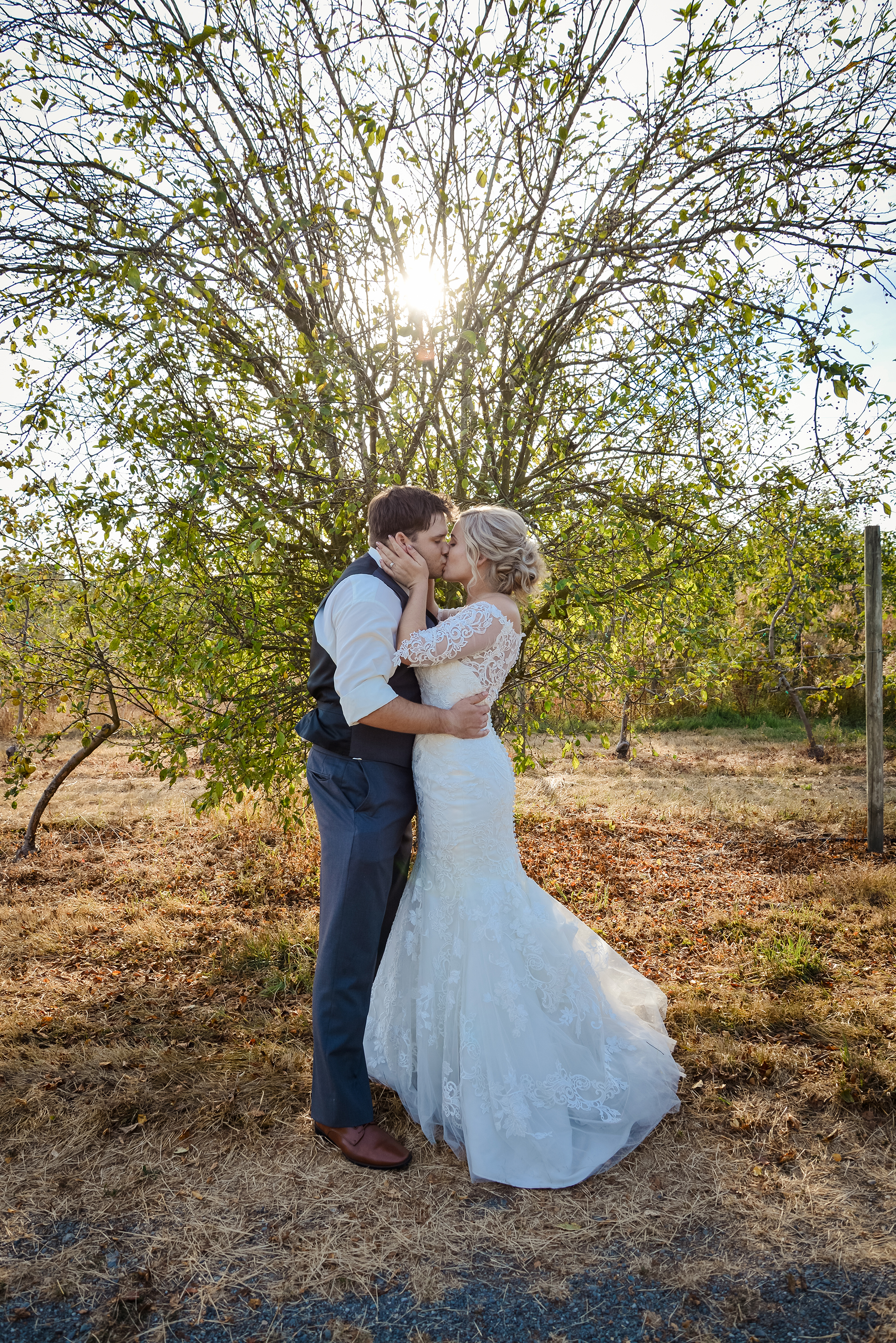 A bride and groom kissing in front of a beautiful sunset